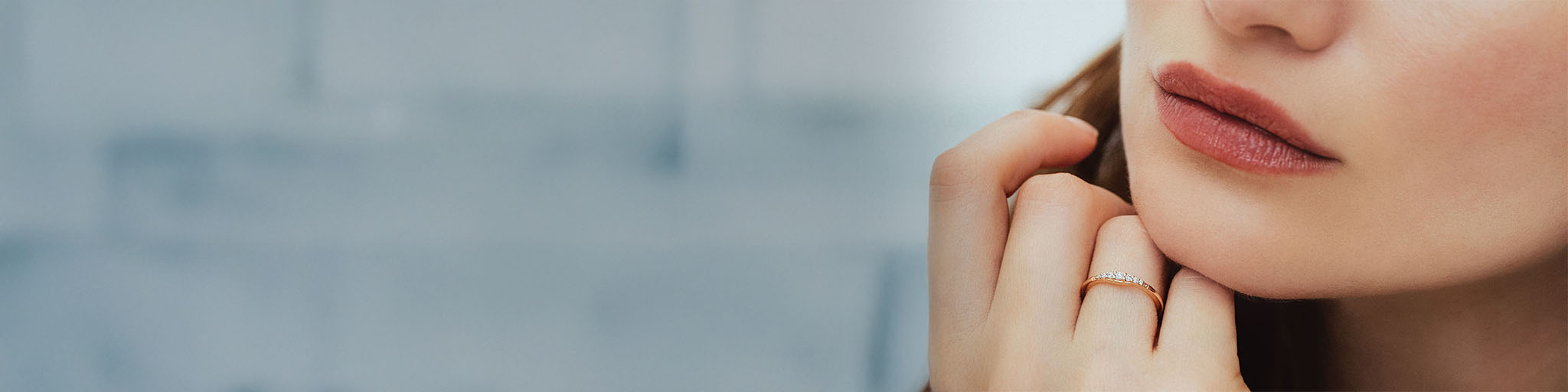 Rose gold wedding ring set with diamonds worn by elegant woman with pink lips on modern urban background