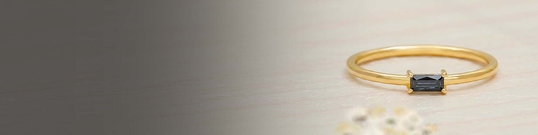 Fine vermeil yellow gold ring set with black diamond baguette, modern minimalist fine jewellery on beige gradient