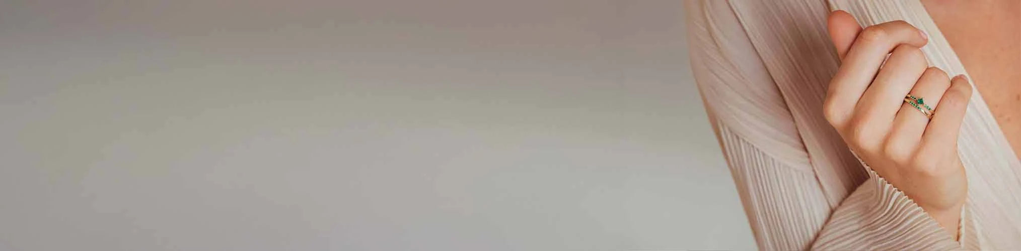 Engagement ring set with green emerald on 18K yellow gold band, worn by elegant woman's hand