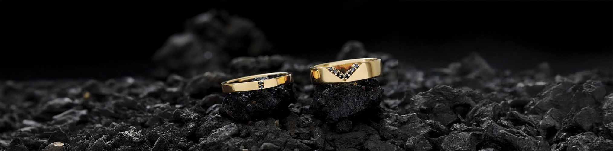 Mars yellow gold wedding rings with black diamonds, modern geometric design on black volcanic stone