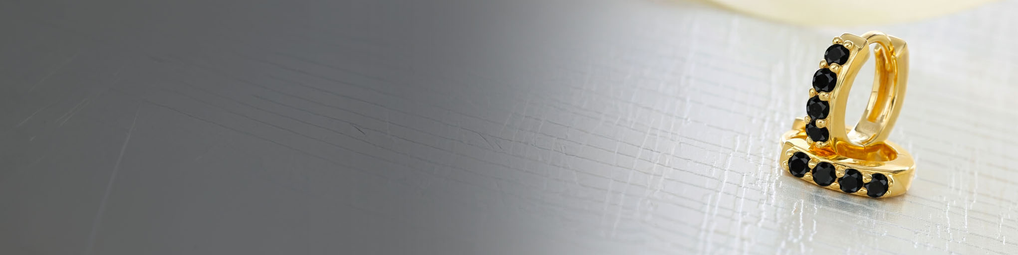 Vermeil hoops adorned with black diamond set, modern fine jewellery on elegant metallized background