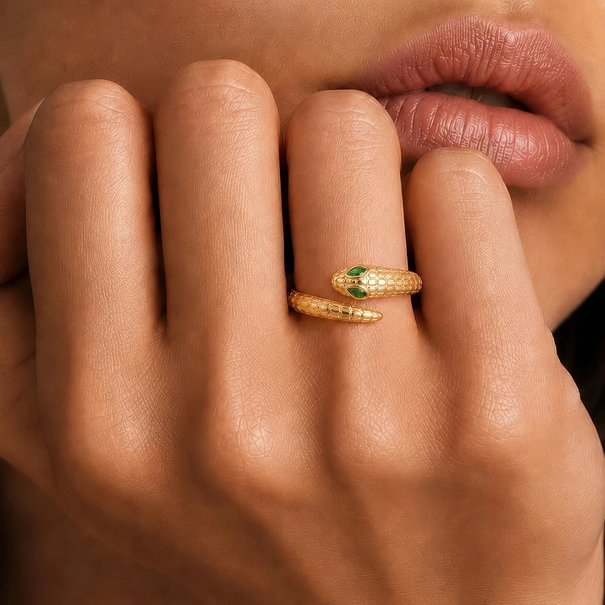 Mehen yellow gold snake ring worn on the finger, marquise emerald eyes