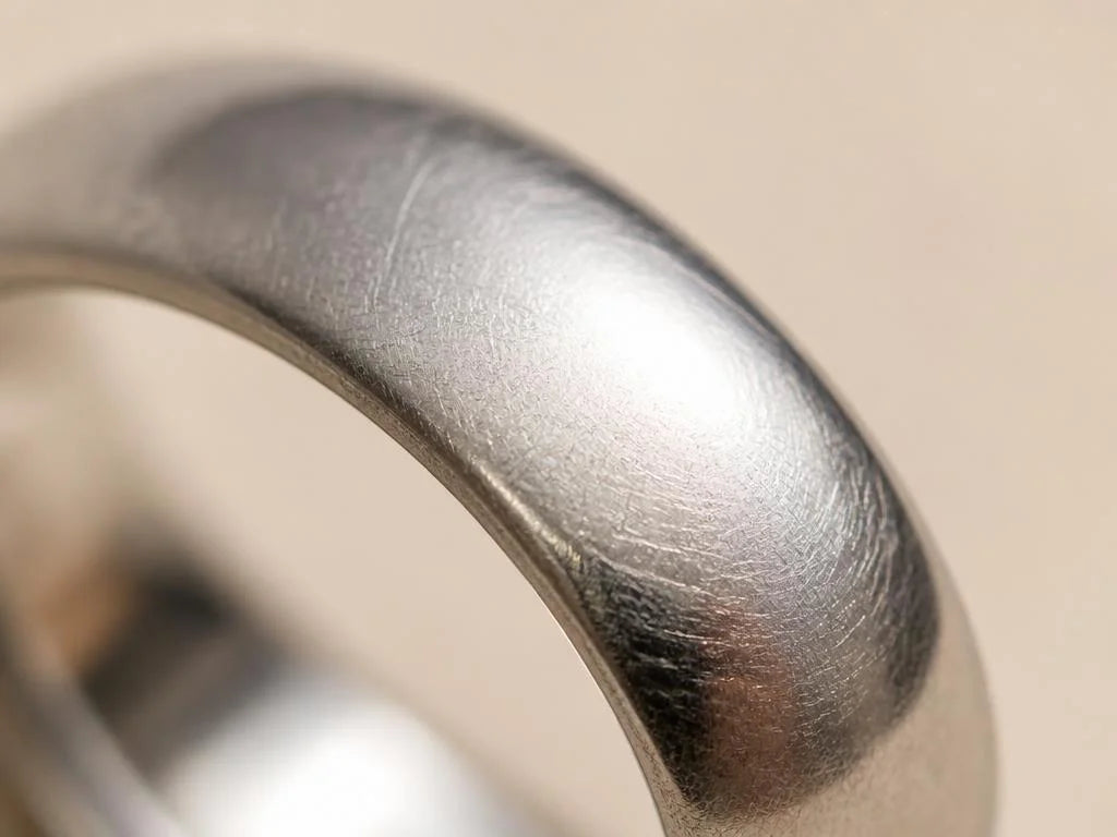 Close-up of the satin patina on a platinum wedding ring worn daily, delicate crisscrossing surface marks