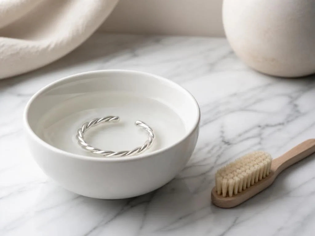 Braided 925 silver bracelet in a bowl of water with a soft brush for cleaning