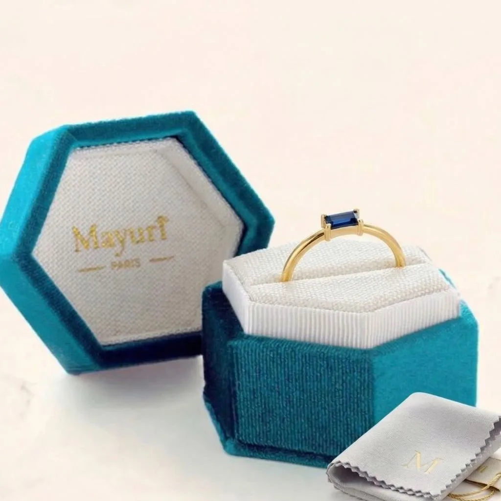Open hexagonal Mayuri jewellery case with a Sapphire ring resting on a white cushion and a Mayuri polishing cloth