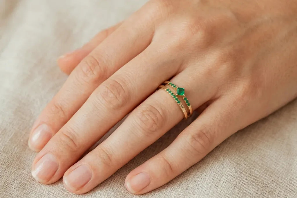 Bague solitaire émeraude en or jaune 18 carats portée au doigt, montrant l'effet visuel sur la main