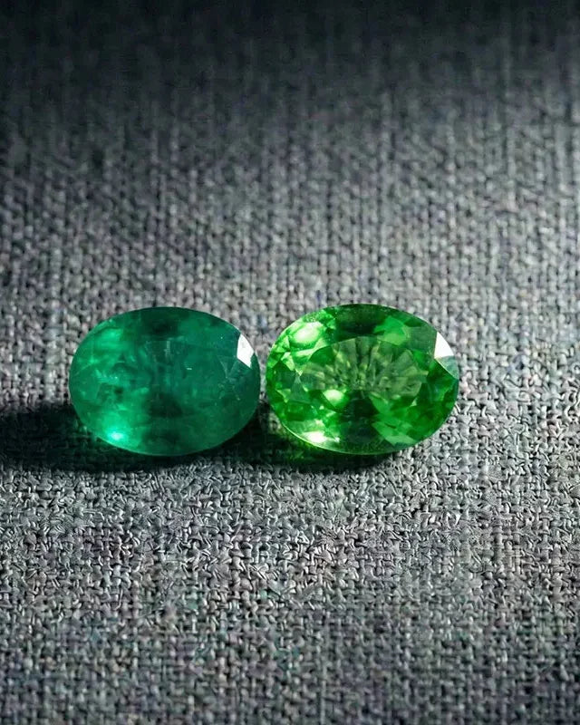 Oval-cut emerald and tsavorite side by side, a comparison of two green gemstones in fine jewellery