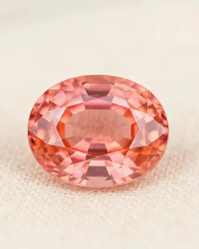 Oval-cut padparadscha sapphire, a rare pink-orange gemstone with brilliant multifaceted reflections