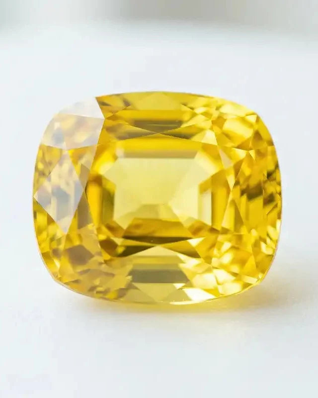 Cushion cut yellow sapphire, a brilliant precious stone with golden hues, symbol of wisdom in Vedic jewellery