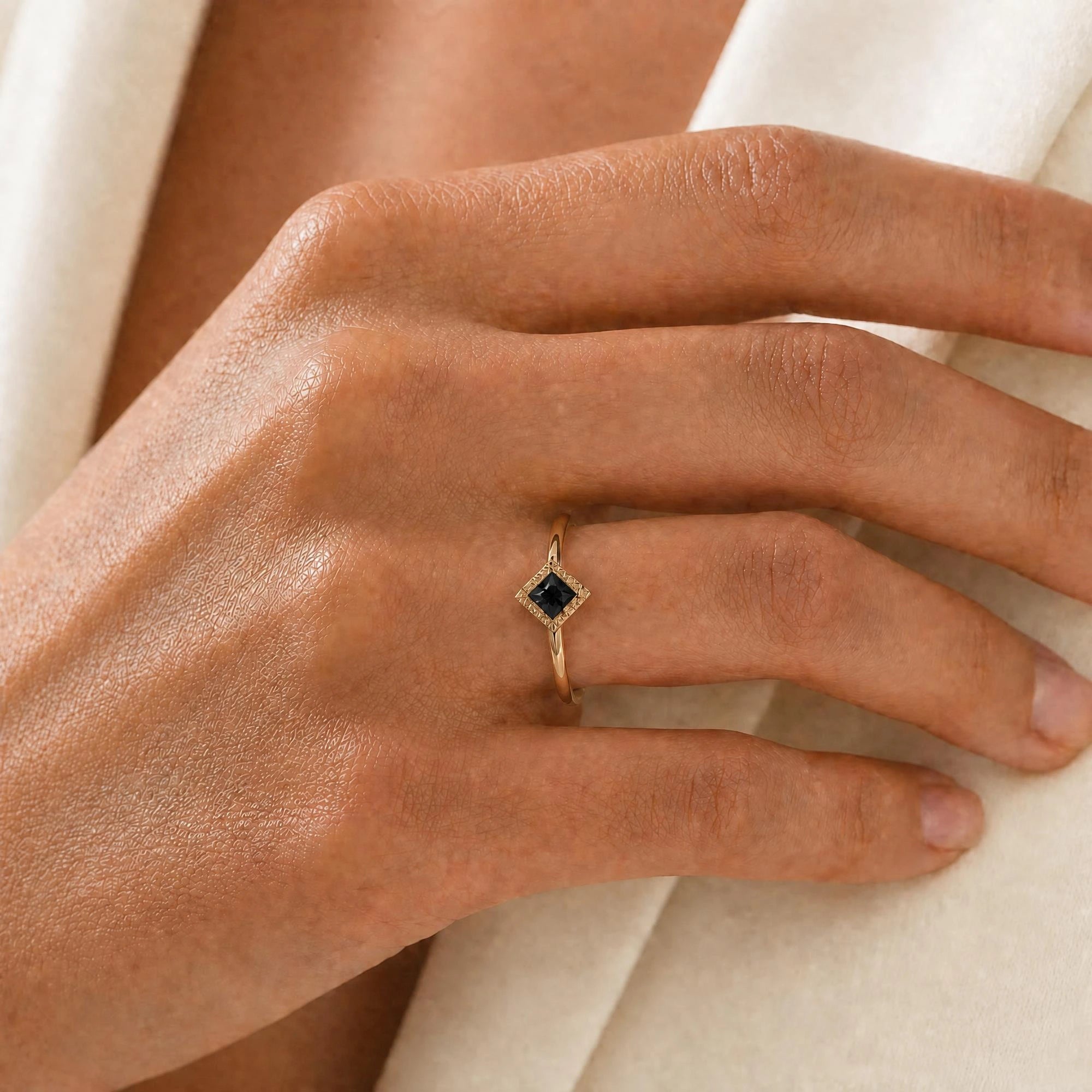 Indrani black diamond engagement ring worn on the hand, princess-cut solitaire in twisted rope setting, 18K yellow gold