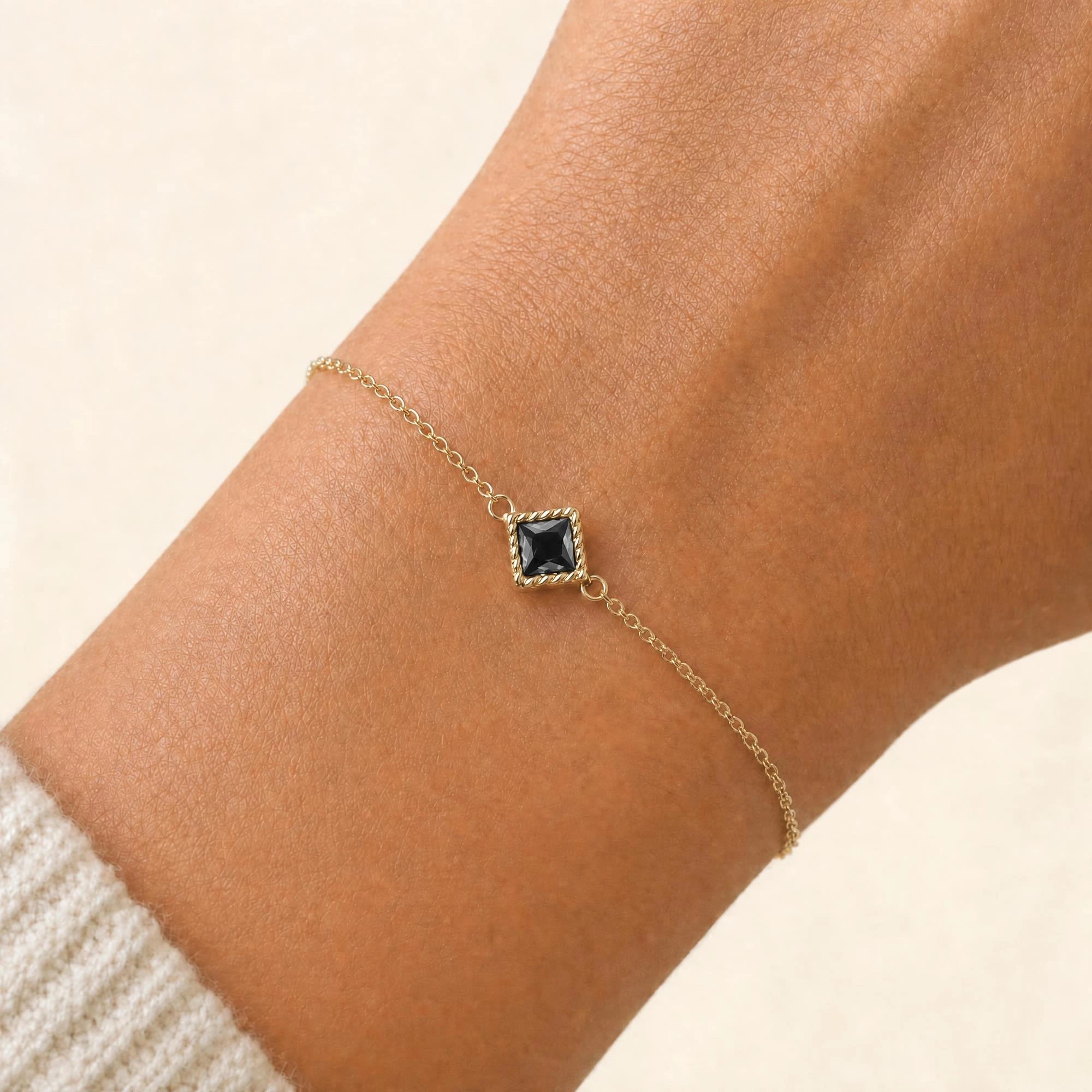 Indrani black diamond bracelet worn on the wrist, princess-cut solitaire in twisted rope setting, 18K yellow gold