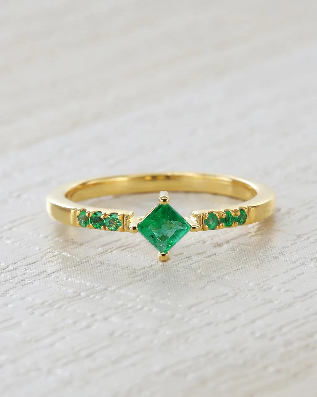Kali ring in gold vermeil set with natural emeralds on light linen background