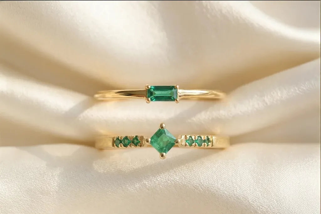 Two Emerald engagement rings in 18K yellow gold by Mayuri, baguette solitaire and pavé designs