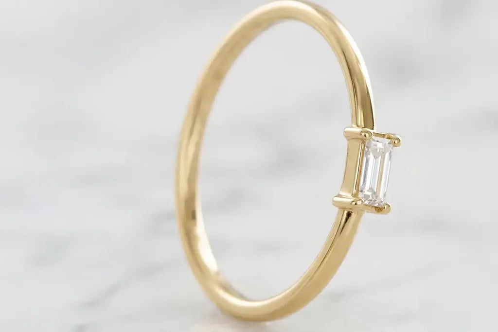 Baguette diamond solitaire engagement ring in 18K yellow gold by Mayuri