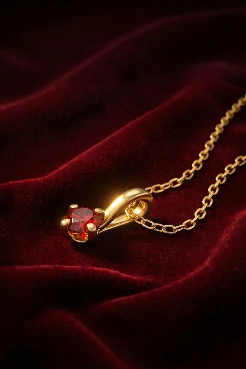 Mayuri Ruby pendant necklace in yellow gold on red velvet, a symbol of passion and royalty