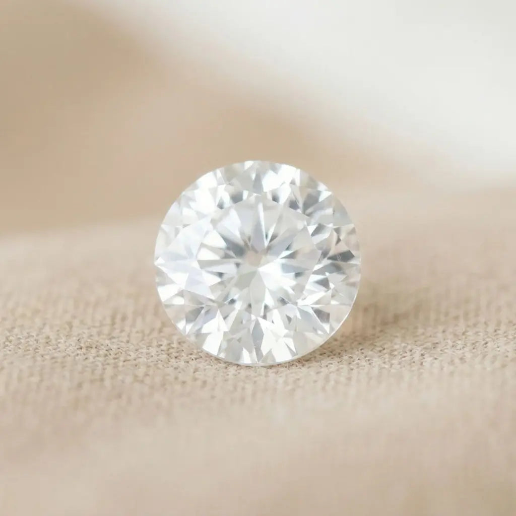 White sapphire, leuco-sapphire, round cut, on beige fabric