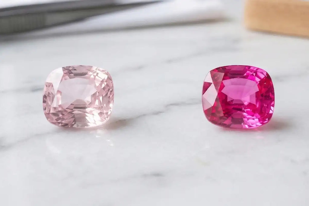 Comparison between a pale pink sapphire and a deep pink sapphire, set on white marble, showcasing the full range of hues